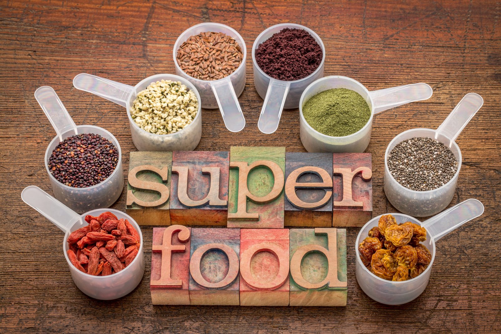 Superfood astratto (erba di grano, bacche di acai, bacche di goji, semi di falce, semi di chia, bacche di physalis, semi di canapa, chicchi di quinoa) - un set di misurini con testo in stampa tipografica su legno rustico CONCETTO Integratori antiossidanti e antiage