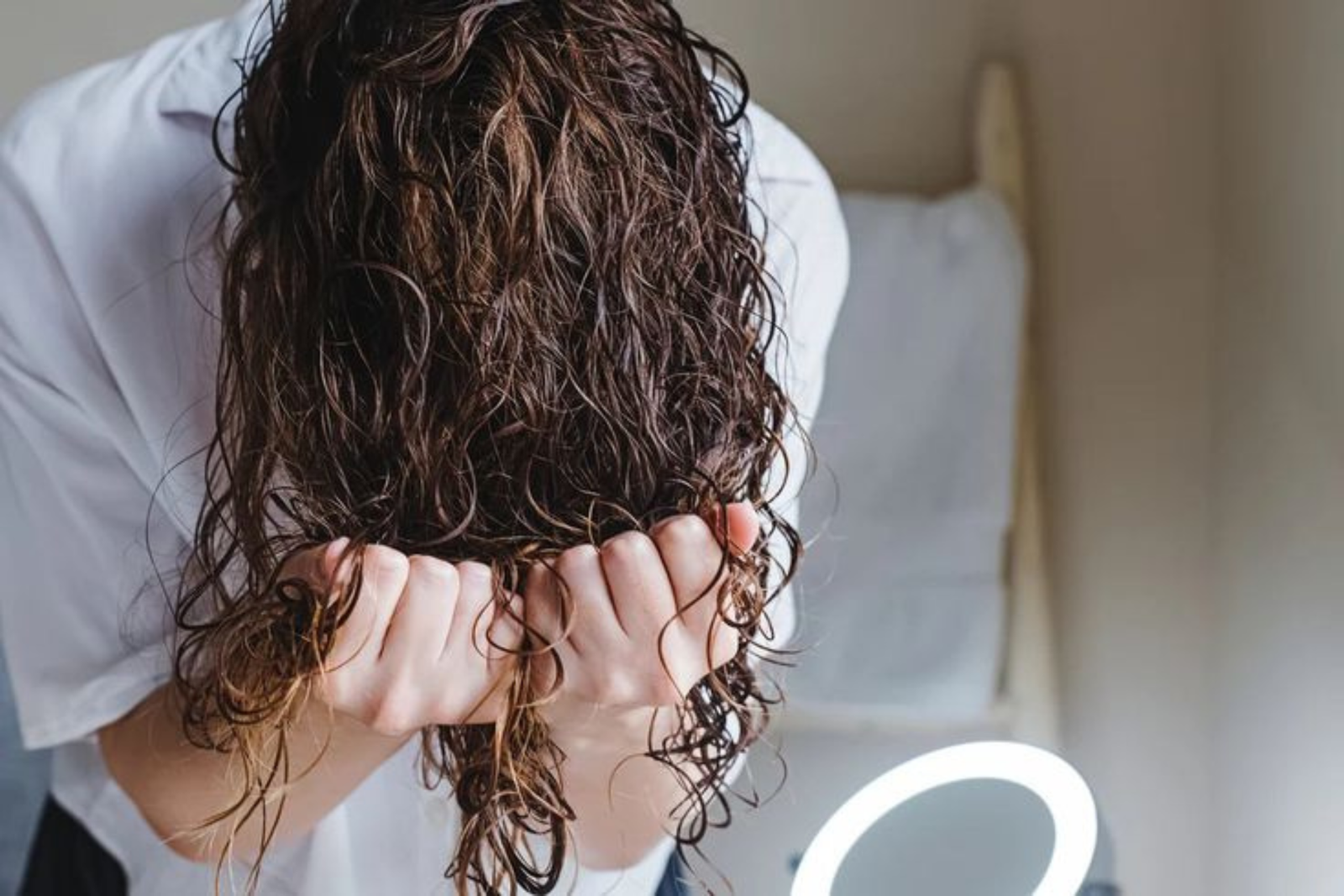 concetto di capelli mossi naturali:- donna fa la tecnica dello scrunch per far formare le onde natural sul capello
