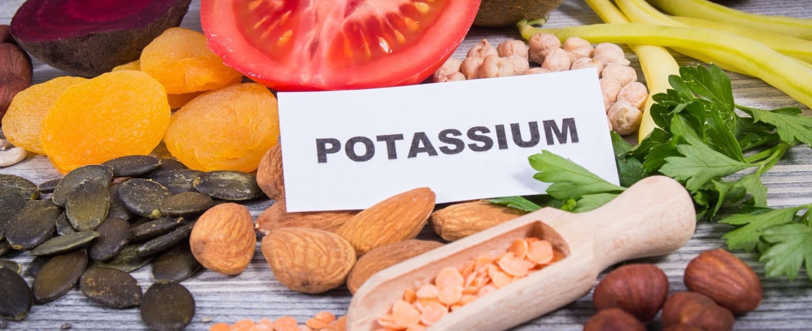 concetto: Gambe gonfie e ritenzione idrica- immagine di alimenti che contnegono potassio con scritta potassium