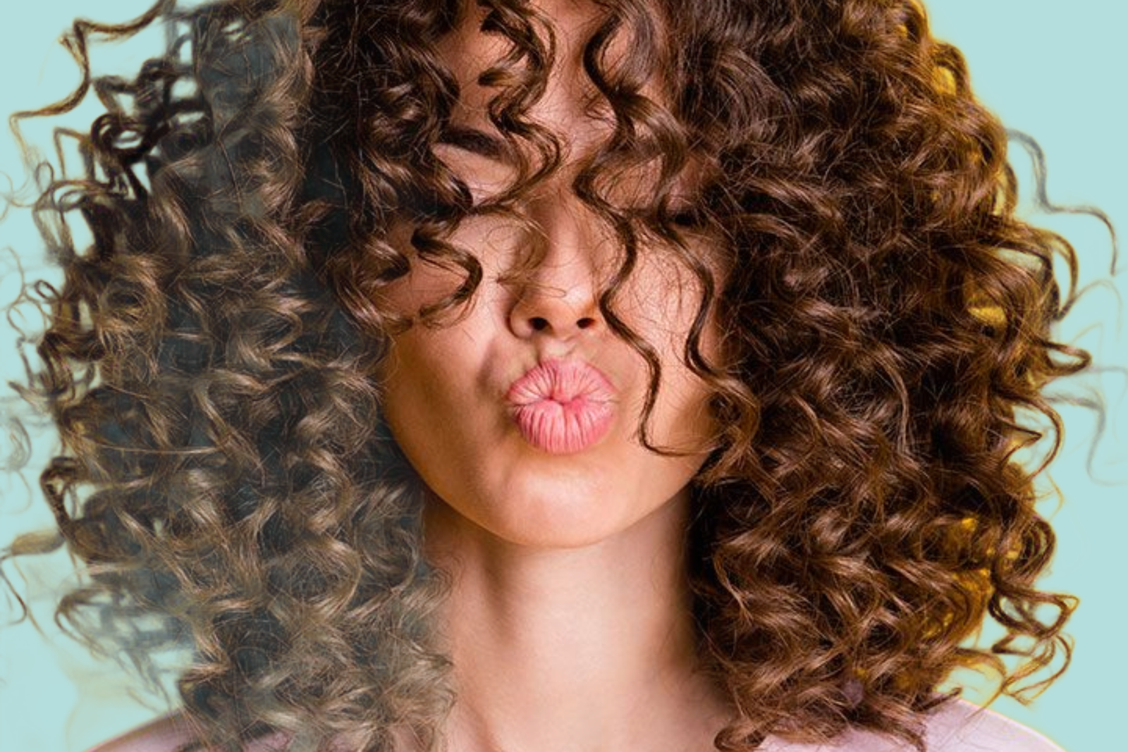 ragazza riccia con occhi chiusi e labbra che sembrano mandare un bacio. primo piano