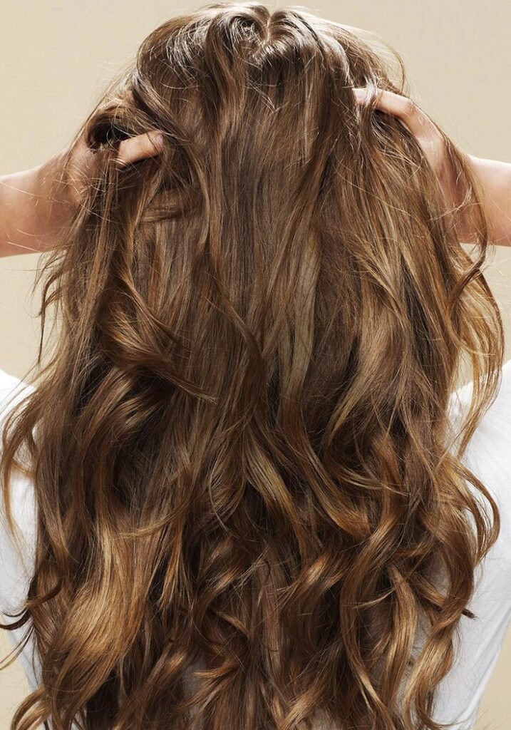 ragazza con capelli lunghi di spalle che massaggia capelli per distribuire lo shampoo secco sui capelli