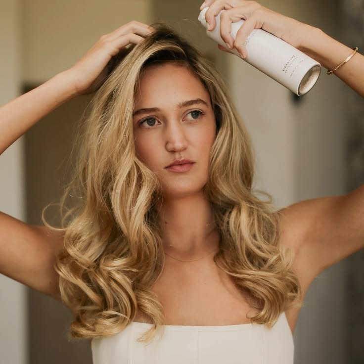 ragazza bionda con capelli lunghi che usa lo shampoo secco 