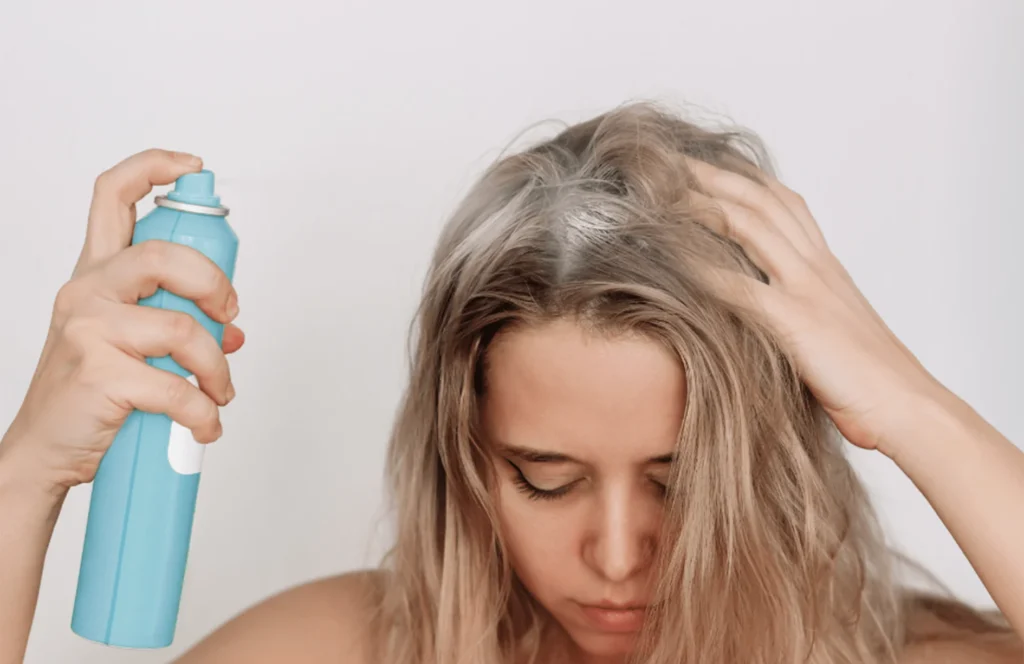RAGAZZA SPRUZZA LO SHAMPOO SECCO SUI CAPELLI 