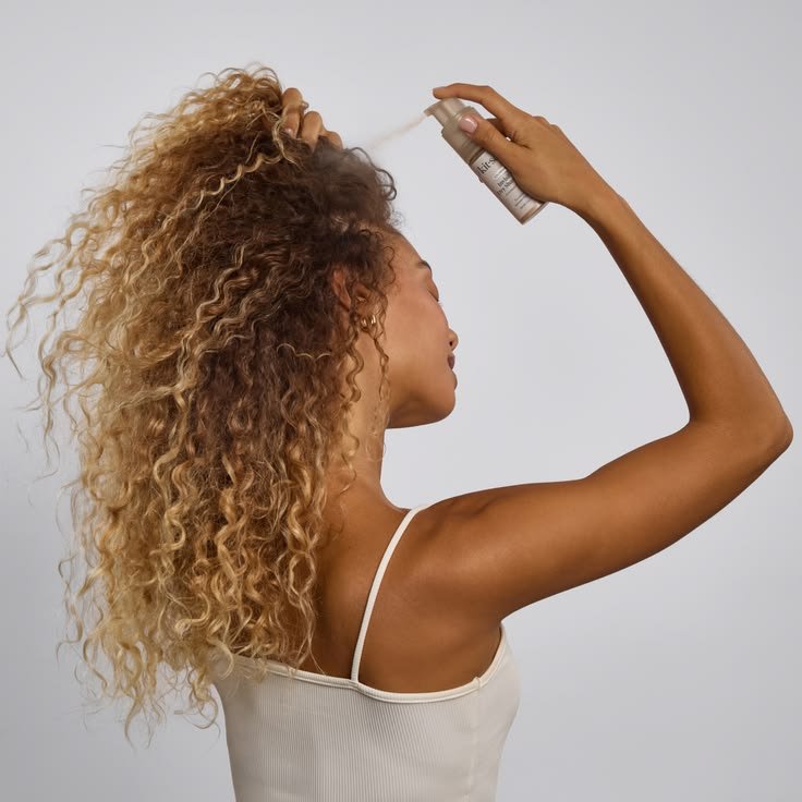 ragazza riccia con capelli lunghi che usa lo shampoo secco 