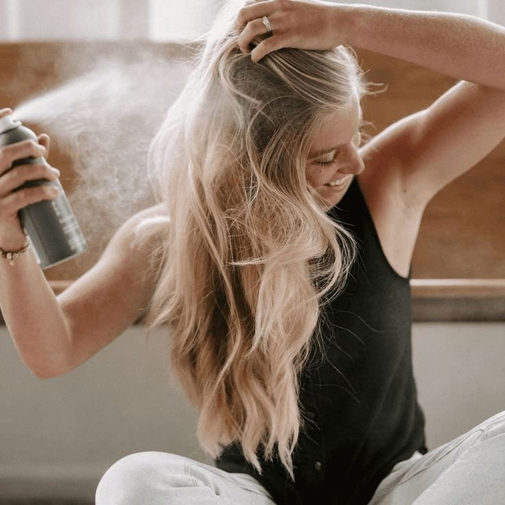 ragazza bionda con capelli lunghi che usa lo shampoo secco 