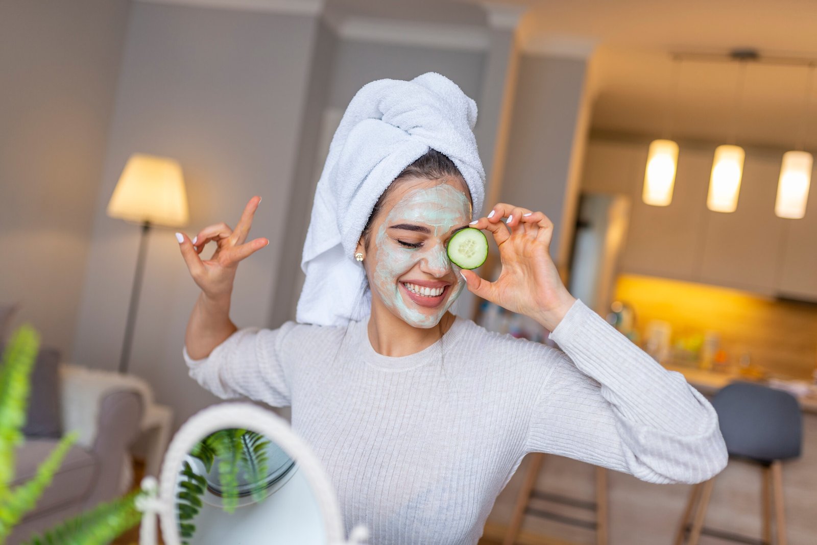 Primo piano di una ragazza con una maschera di bellezza sul viso che si guarda allo specchio. Concetto di cura della pelle grassa e mista e pori dilatati